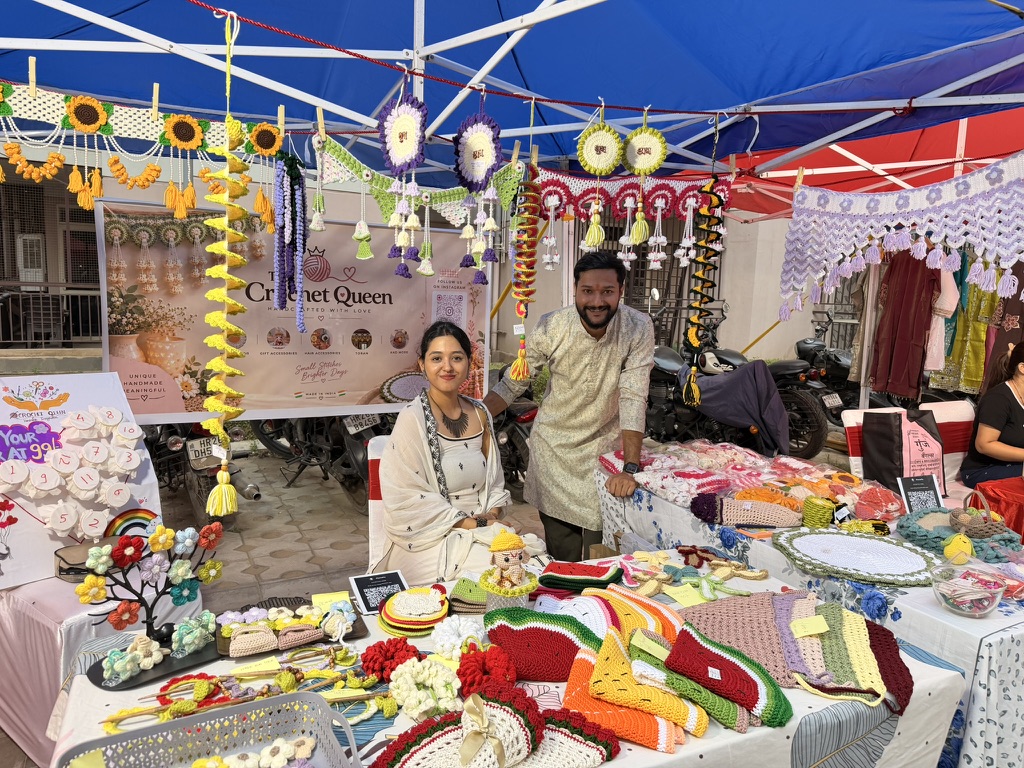 Shraya at The Crochet Queen stall, surrounded by her torans, Shubh Labh hangings and placemats